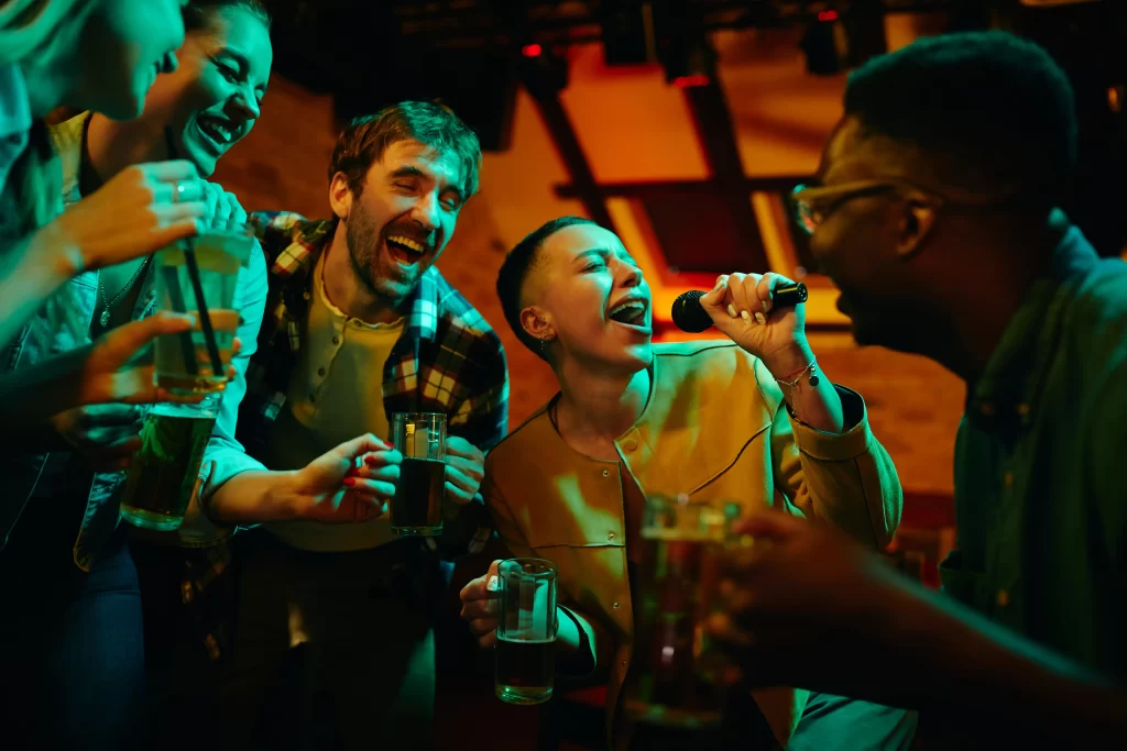 Five friends enjoying and singing while holding a glass of beer